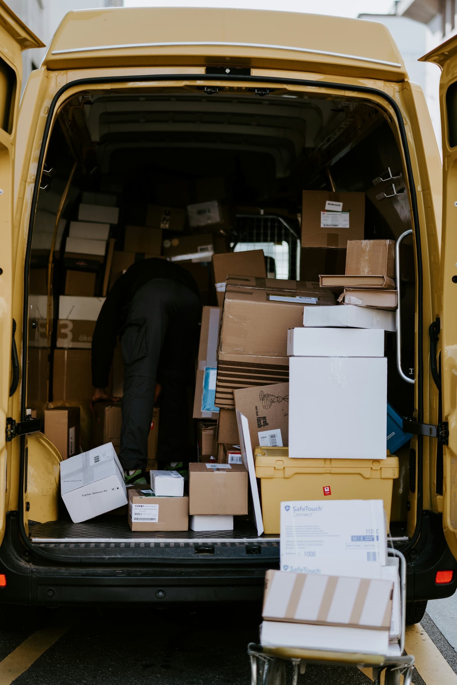 Courier loading cardboard boxes into a delivery van